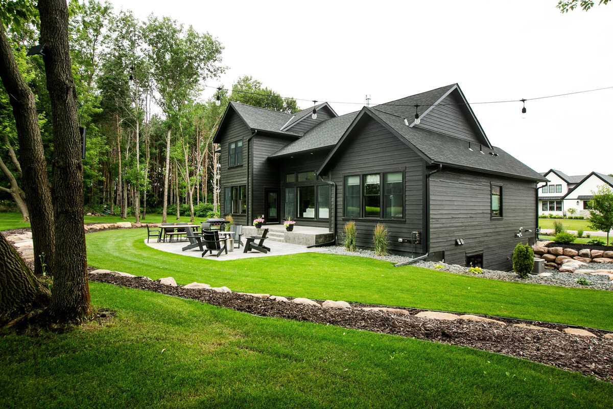 Exterior view of custom home in Otsego, Minnesota with black siding, large patio and windows built by Cornerstone Custom Builds