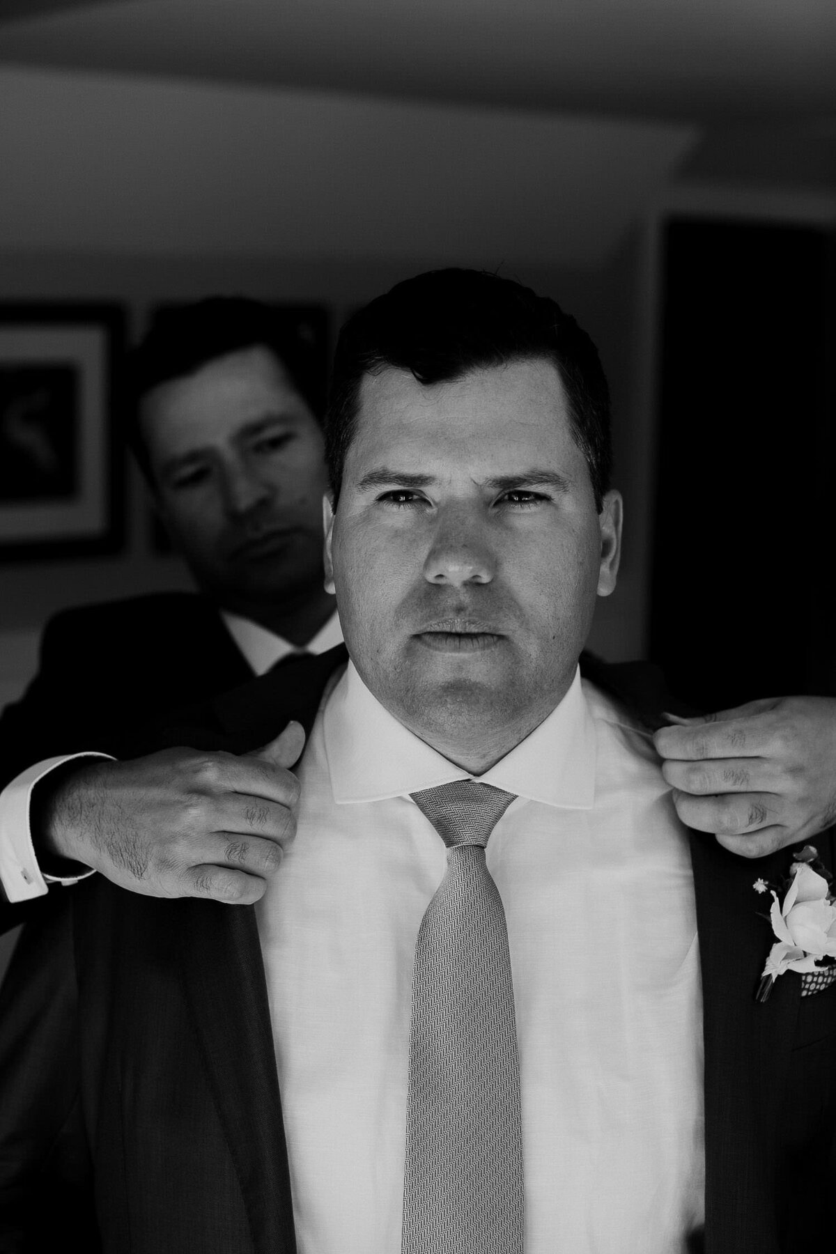 Black and white groomsmen putting on grooms navy suit