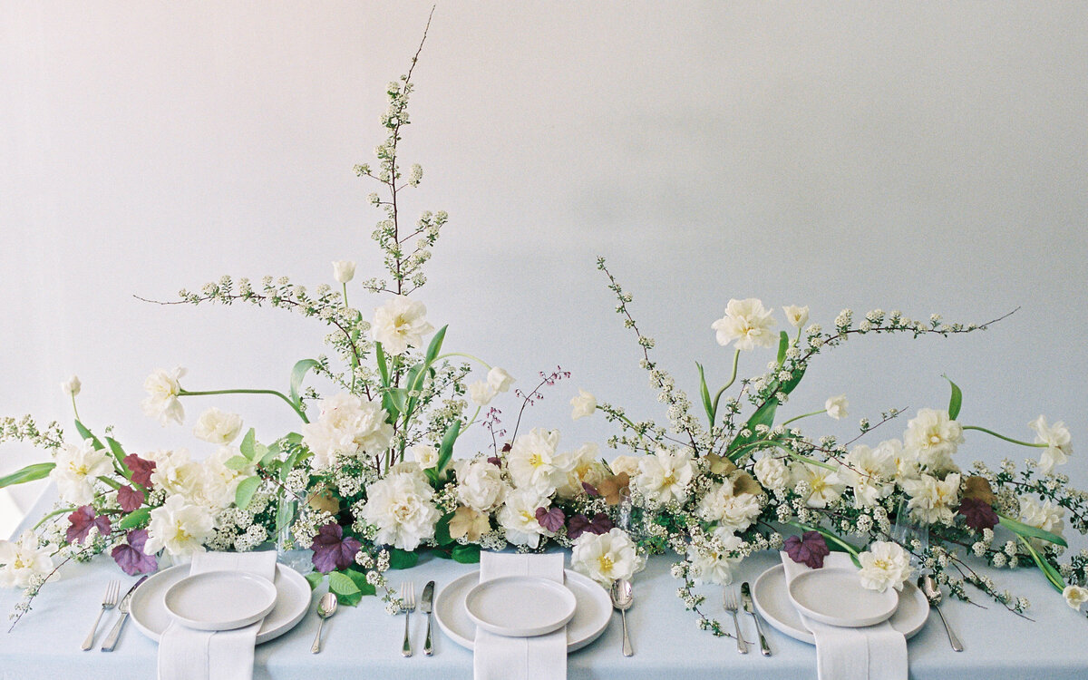 Lush, white spring flowers form a long, low table centrepiece at a Montreal wedding.