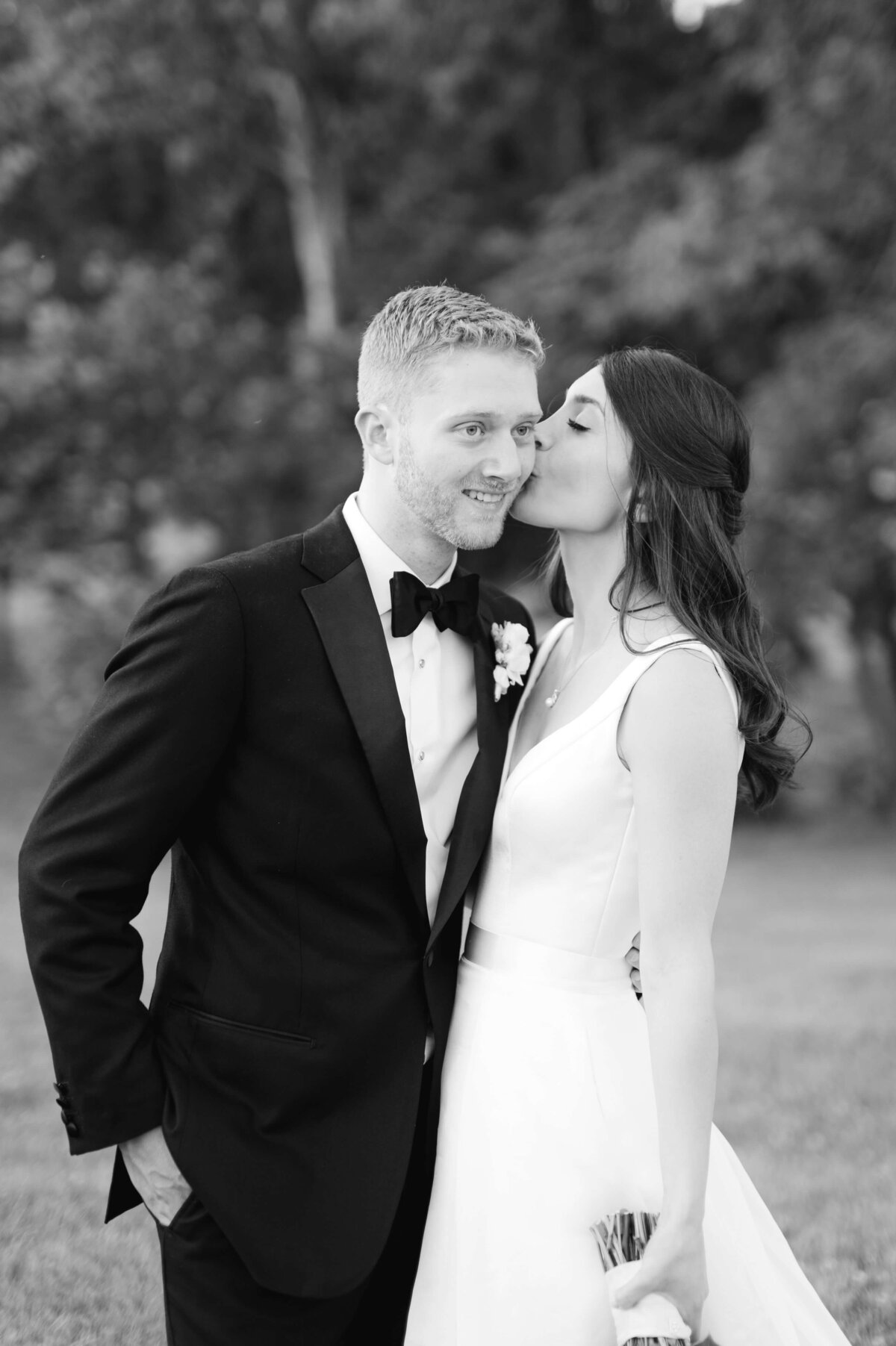 Timeless image of a bride kissing her groom on the cheek during wedding portraits