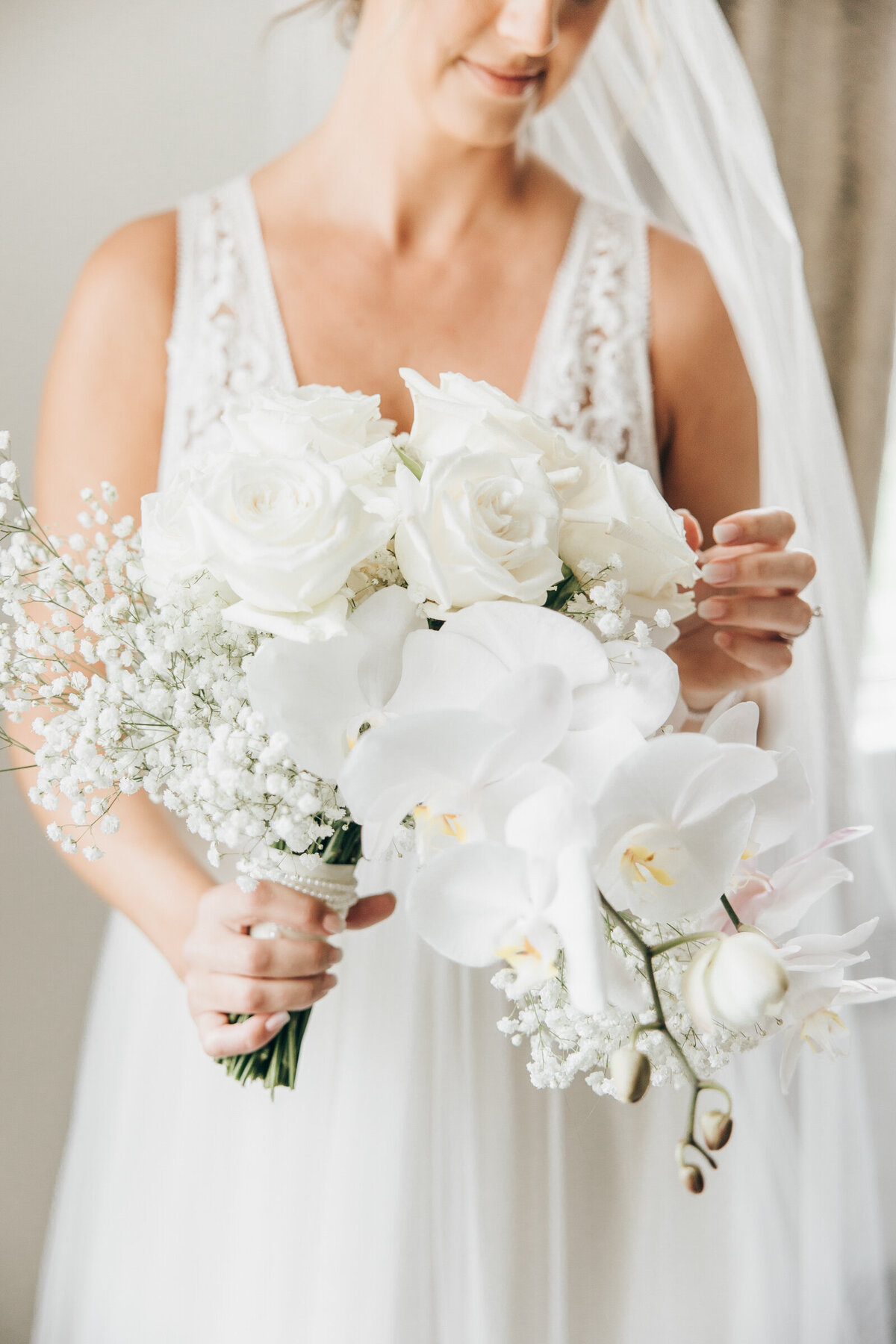 Gorgeous, cascading, white wedding bouquet with white orchids, baby's breath and white roses