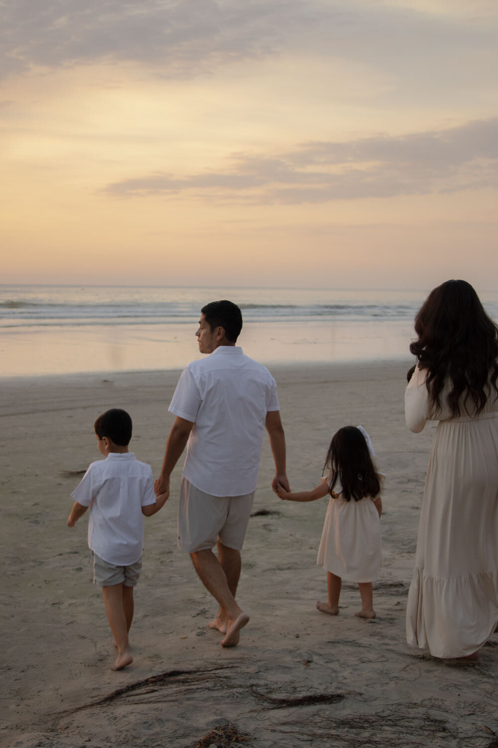 A family walking together along the beach, with the ocean behind them