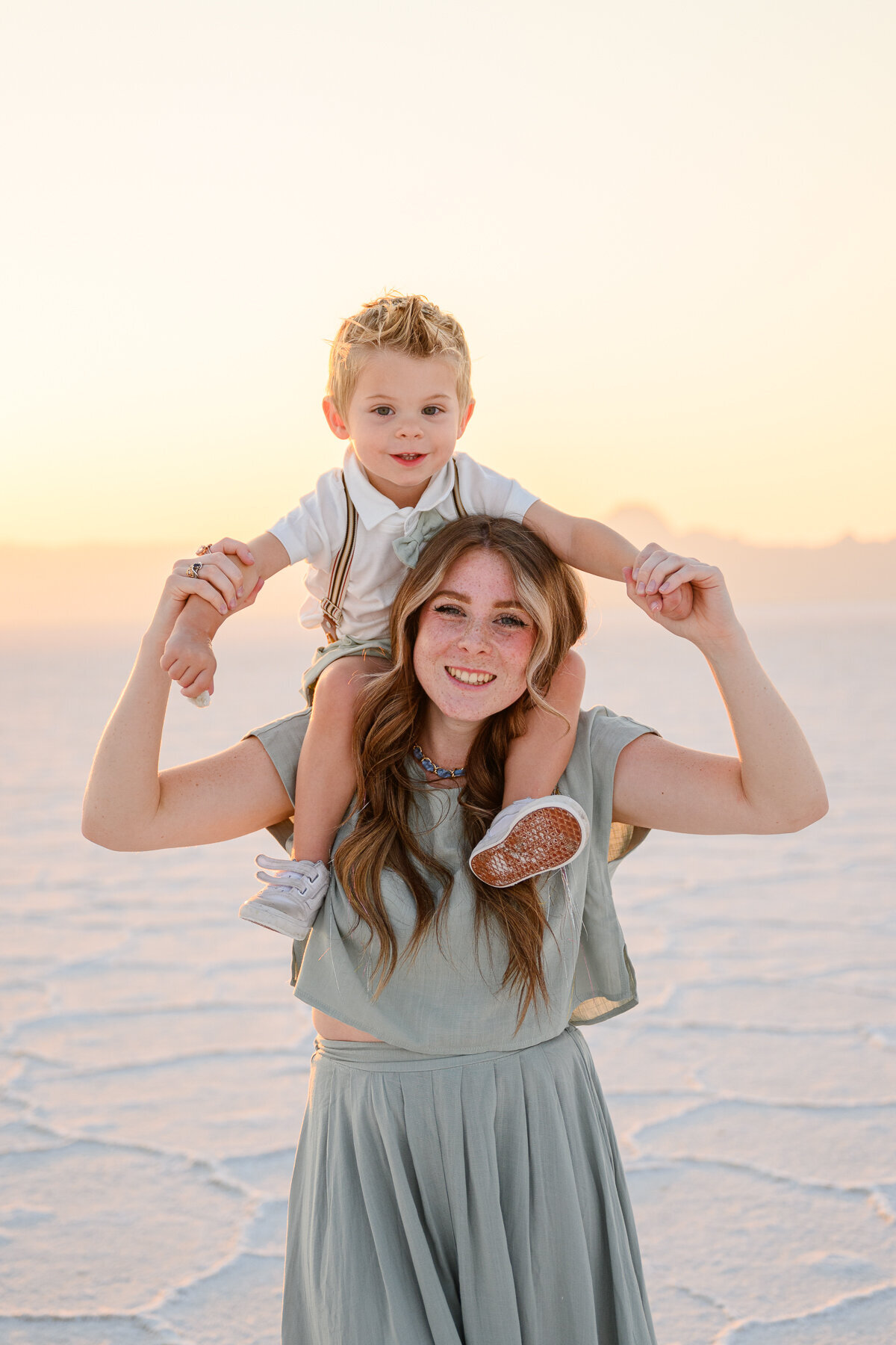 mom and son on shoulders at sunset at the salt flats in utah for family photography