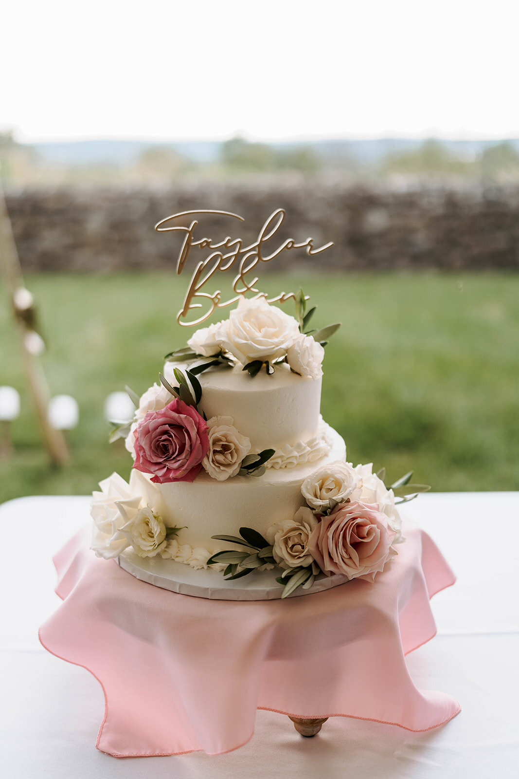 simple white and blush wedding cake with custom topper