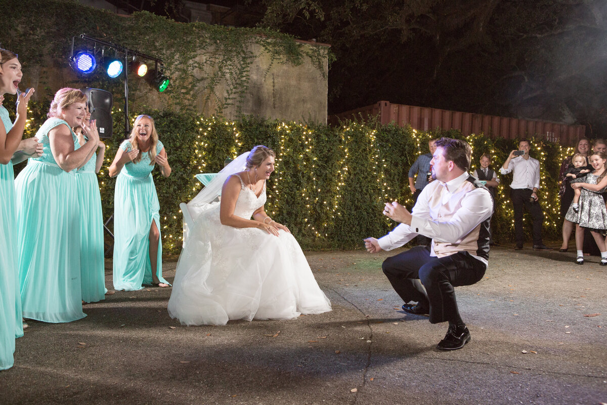 The groom dances for his bride at the wedding reception before grabbing the garter from her leg at The Richards DAR House in Mobile, Alabama.