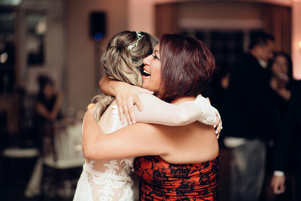Wedding Photograph Of Woman In Red Dress Hugging  The Bride Los Angeles