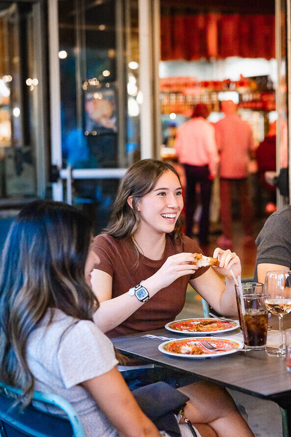 Woman smiles and eats pizza at Ace Restaurant.
