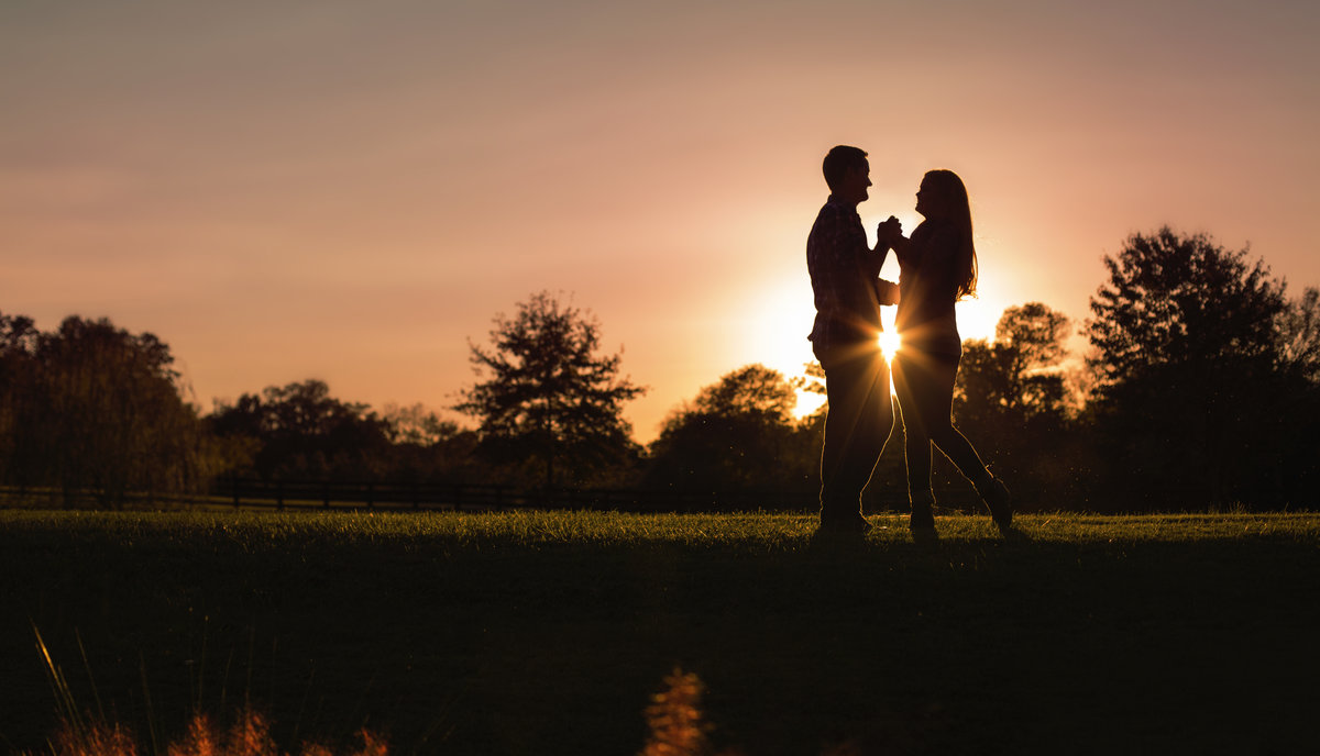 A couple shares a moment at sunset silhouette at Morning Glory Farm in  Charlotte NC during their engagement session