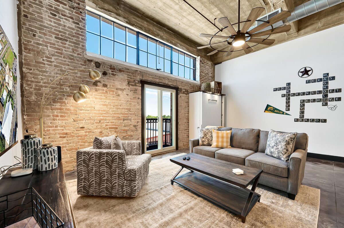 Living room with exposed brick in this one-bedroom, one-bathroom vintage condo that sleeps 4 in the historic Behrens building in the heart of the Magnolia Silo District in downtown Waco, TX.