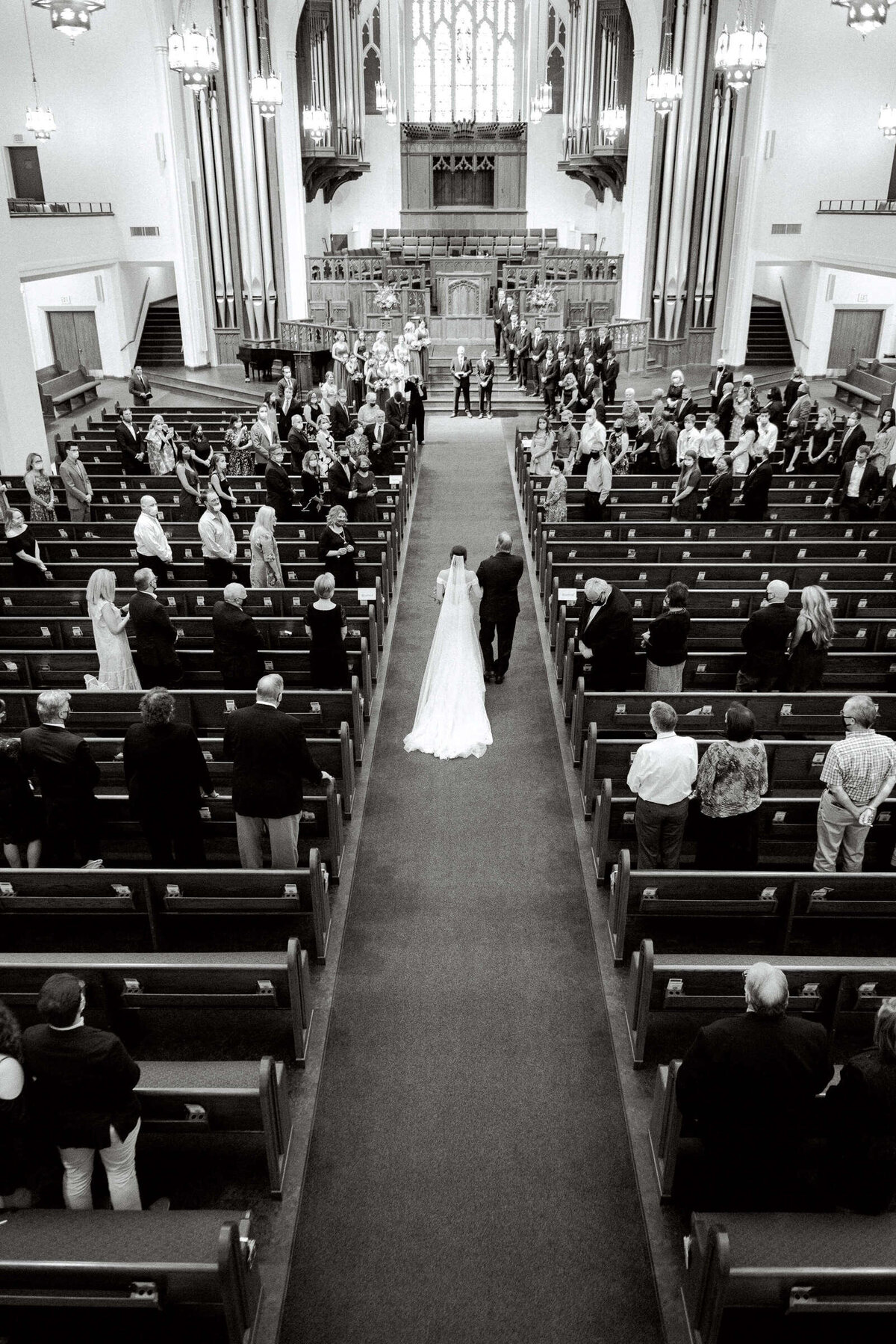 Black and white photo of bride and her father walking down the aisle at The 4Eleven cathedral in Fort Worth