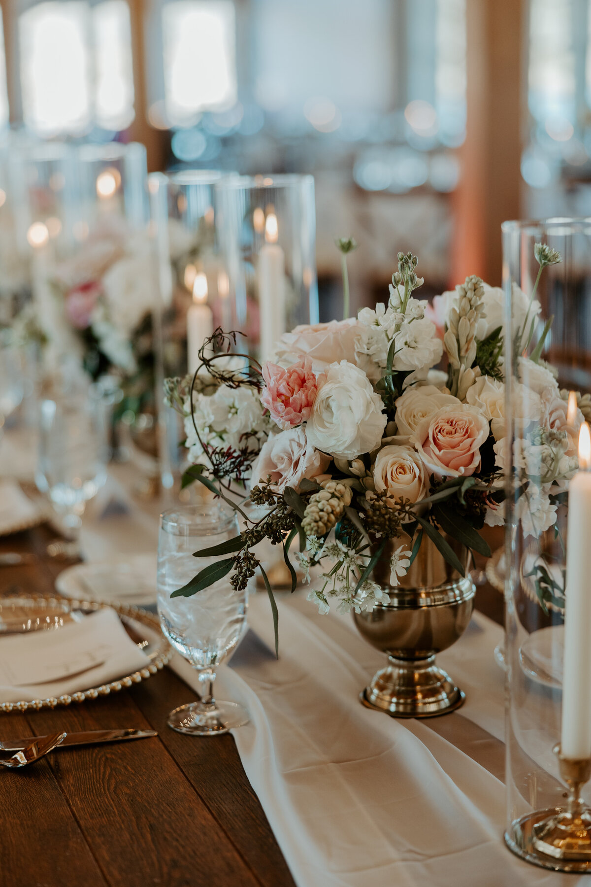 Blush and cream florals in a gold container on farm table