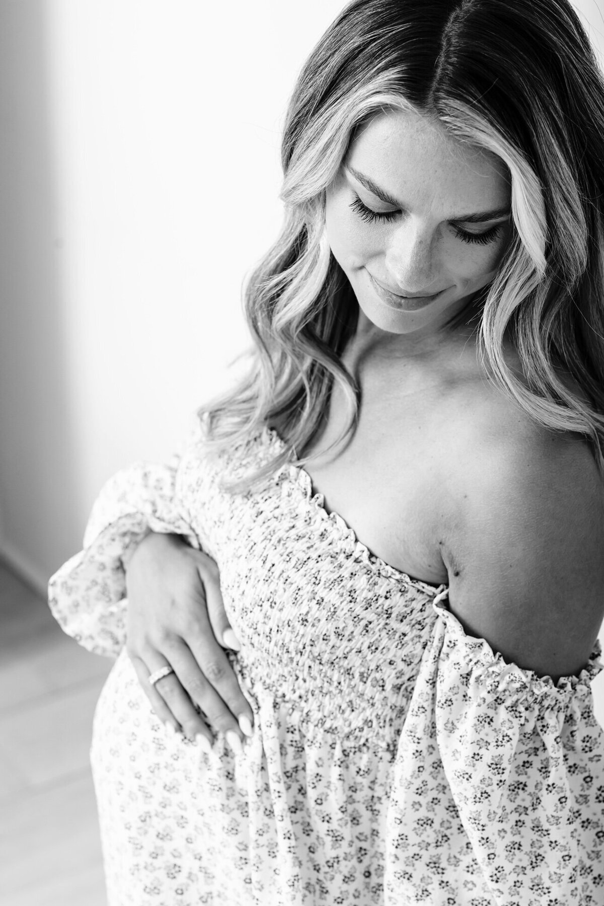 Artistic black and white maternity image featuring a pregnant woman in a soft, natural pose