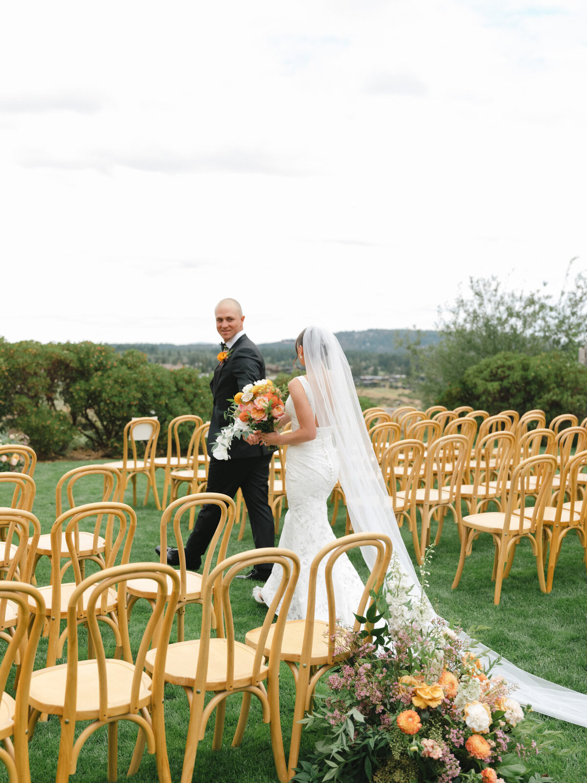 Modern wedding couple in a luxury wedding aisle with florals and wood chairs representing full service design and calligraphy by Life in Letters.