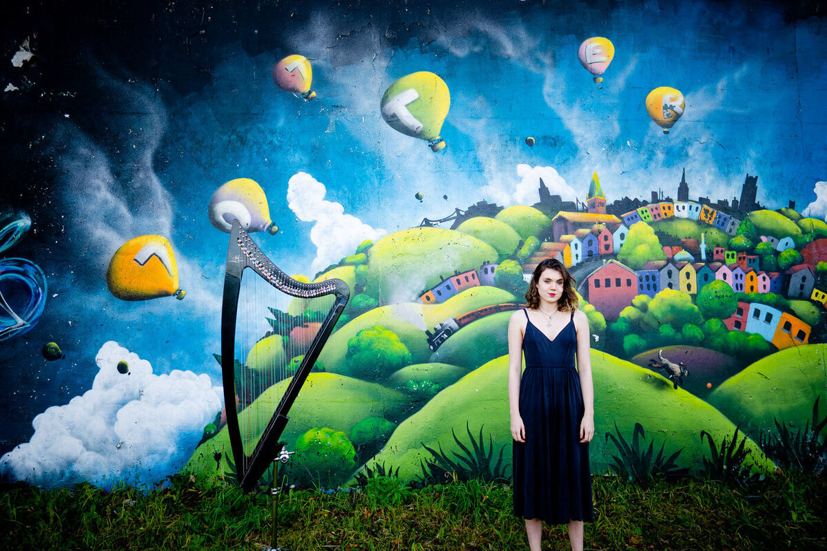 a harpist with her harp in front of a graffiti wall - Edgy photograph