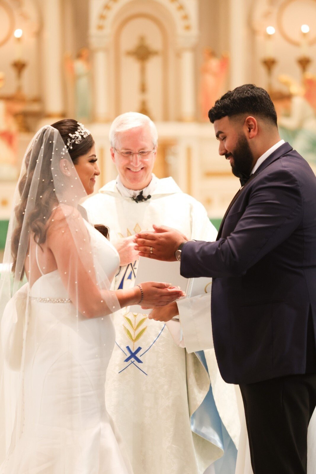 Bride and groom exchange wedding rings with smiles during ceremony at Union Club Hotel." cell