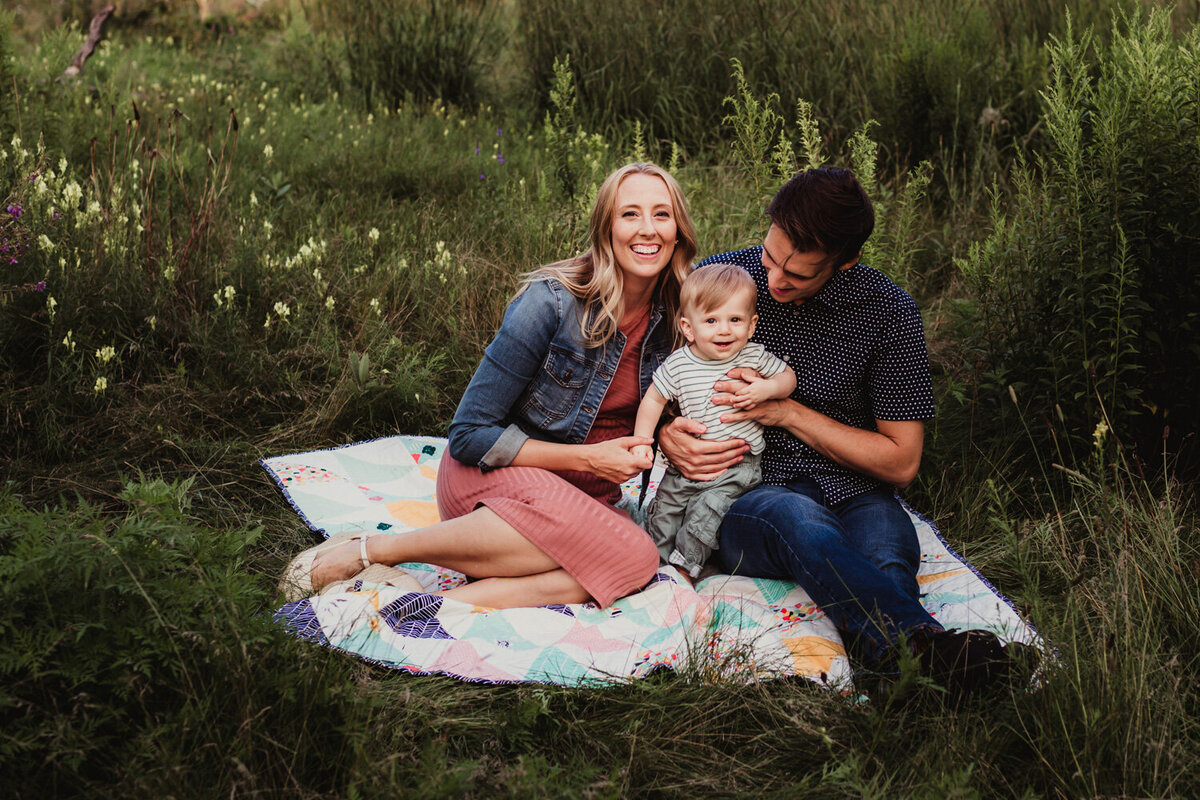 Couple and baby boy sitting on quilt during family portrait session