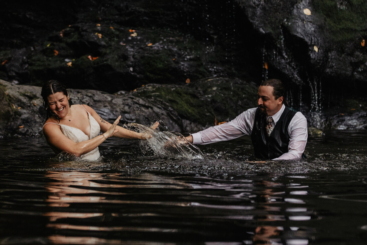 Wedding couple playing in water at their Smoky Mountain elopement in Tennessee