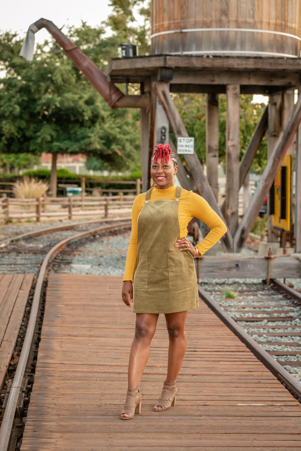 Black woman in yellow and green in front of a water tower