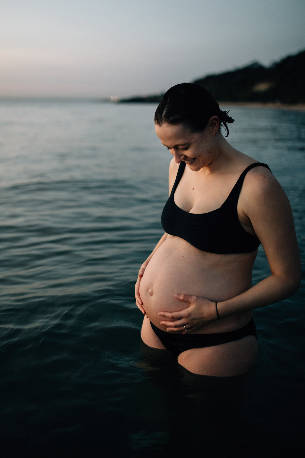 woman holding pregnant belly in ocean,  maternity photography Melbourne by And So I Don't Forget Photography
