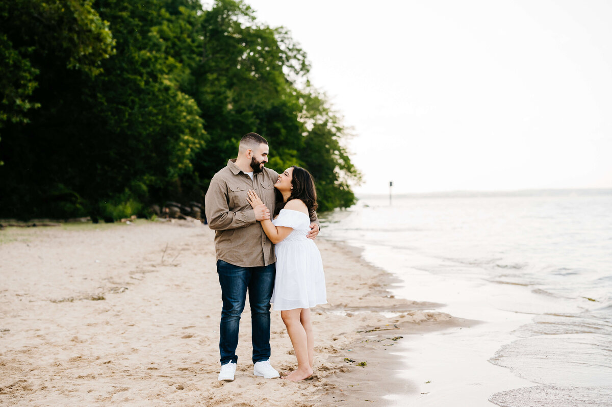beach engagement photos with man and woman embracing on the beach for couples photography  with Virginia wedding photographer