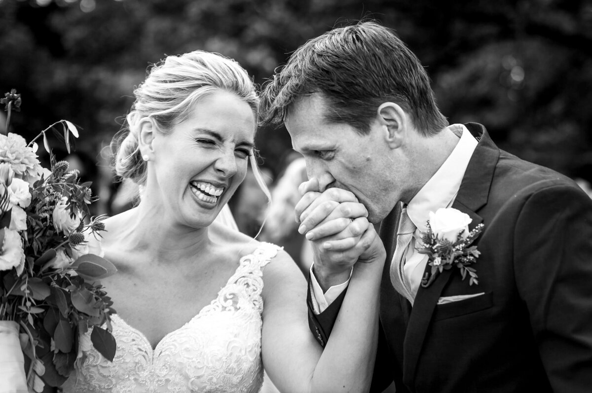 groom kissing the hand of his bride after getting married outside of Rose Bank winery