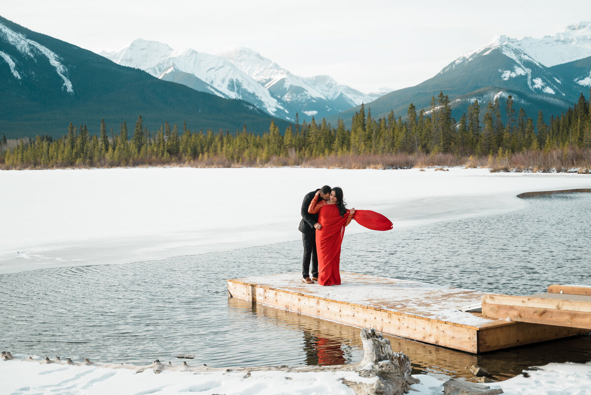 Engaged couple shares romantic moment on frozen dock in Banff’s Vermilion Lakes.