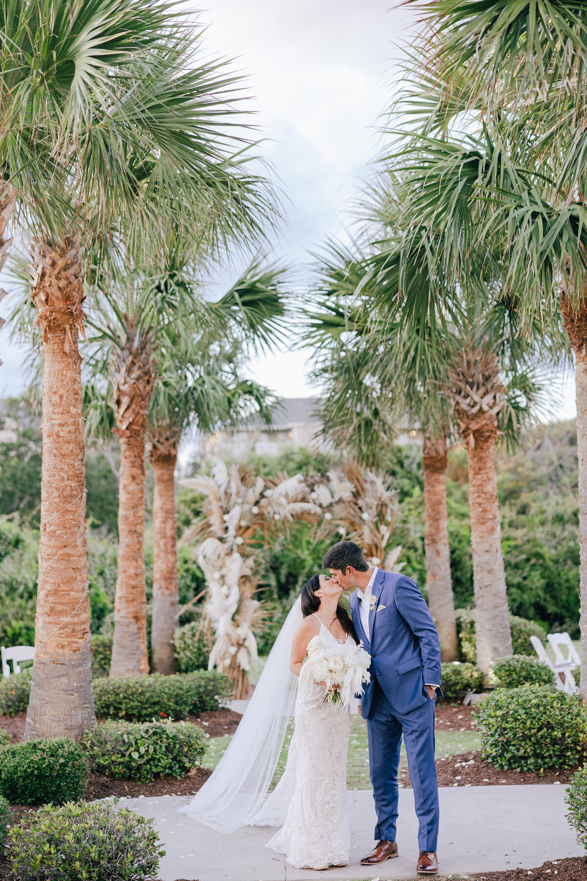Bride and groom sharing a tender moment beneath palm trees, captured by a Destination Wedding Photographer.