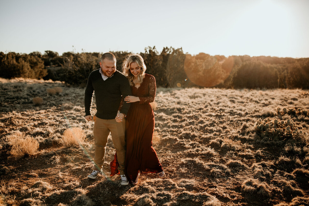 woman holding fiancés arm walking in the desert