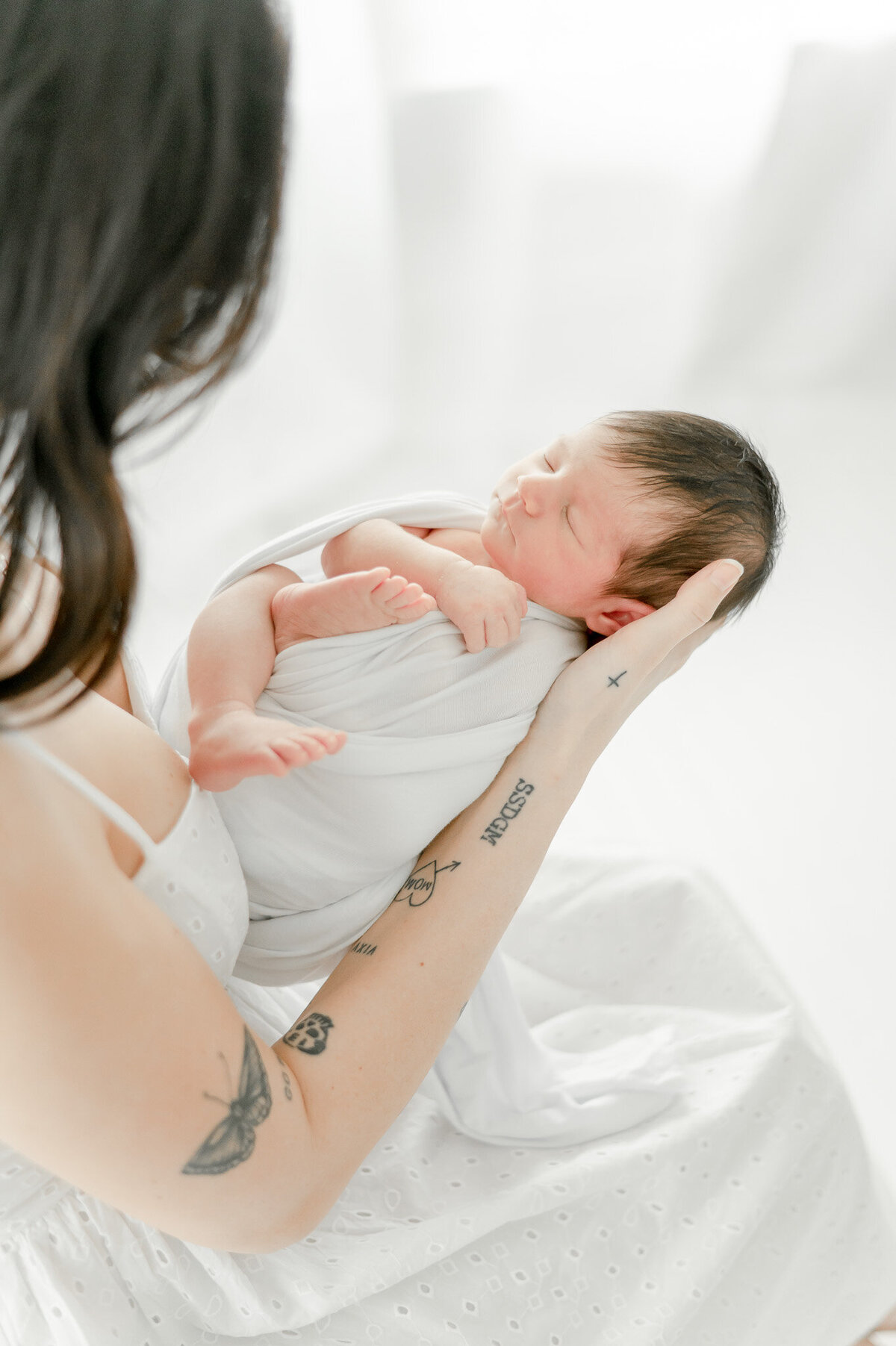 Baby sleeps in her mother's arms with tattoos