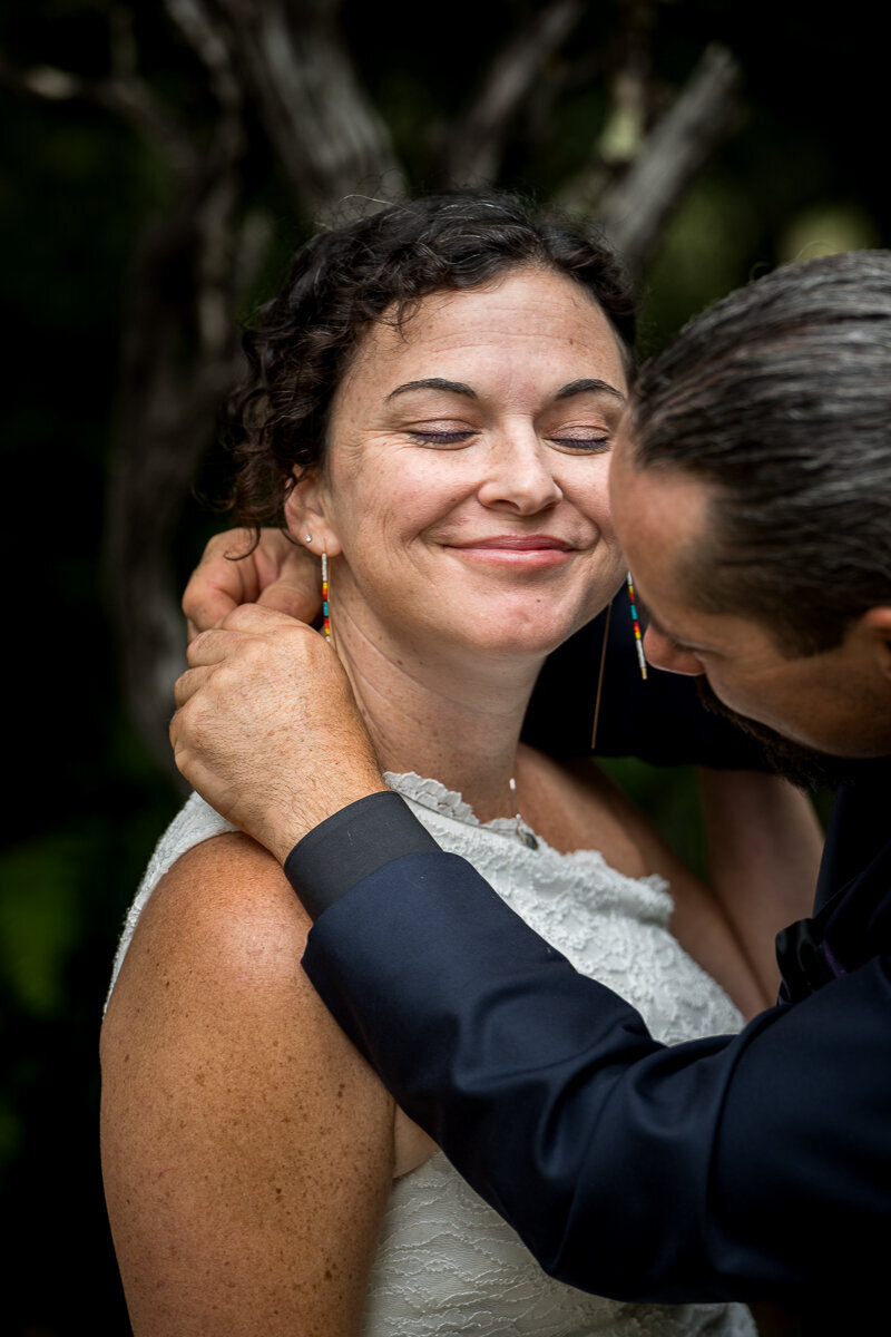 A touching wedding moment as the groom gently places a necklace on the bride during their ceremony in Eureka, CA, symbolizing love and commitment in front of family and friends.