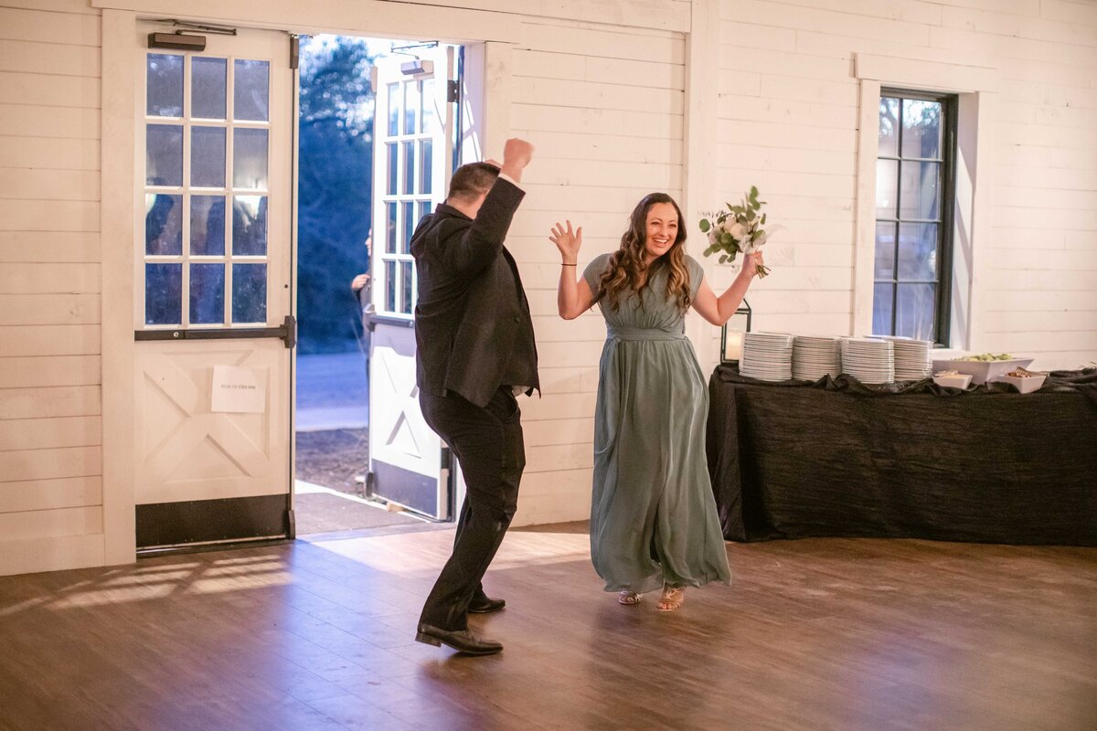 bridesmaid and groomsman leap for joy entering wedding reception at Morgan Creek Barn in Dripping Springs