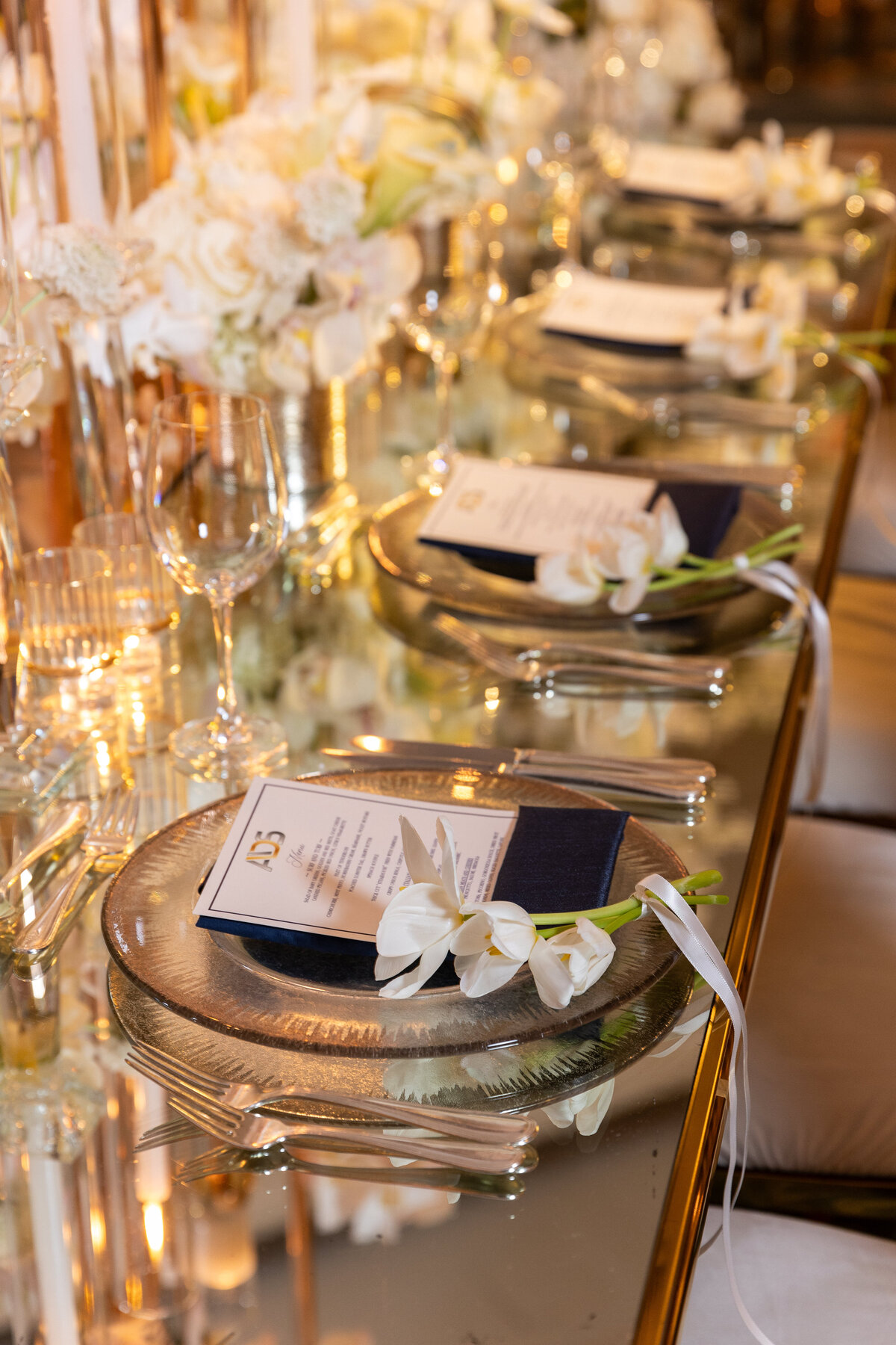 Long golden table with crystal plates with an  orquid on top