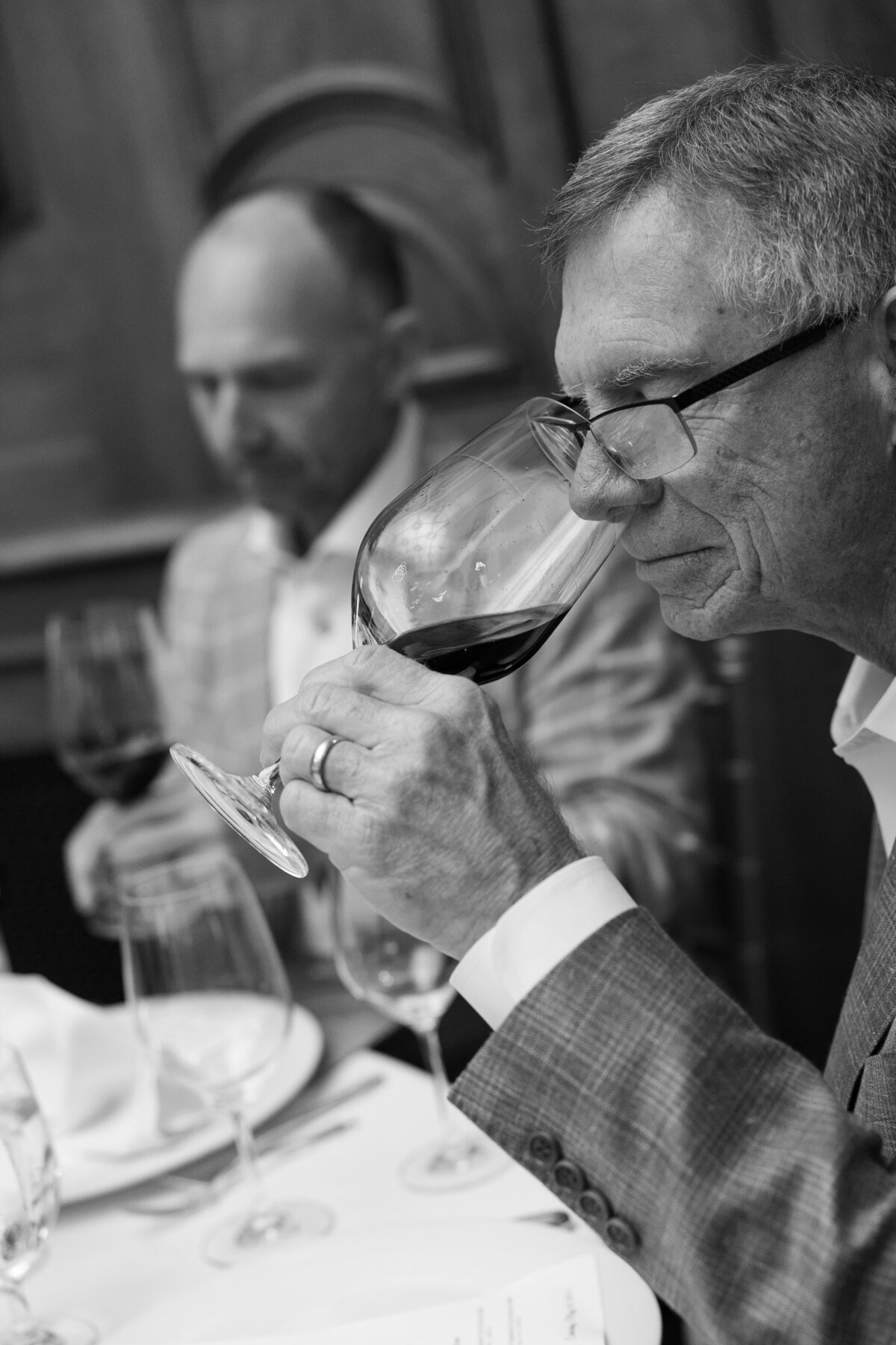 two older males drinking wine