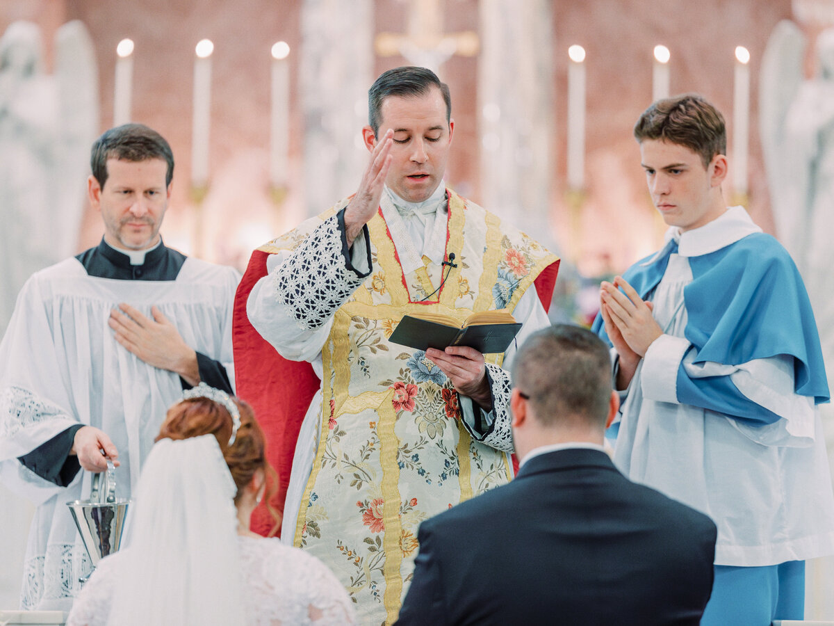 Priest blessing bride and groom during St Leos Oratory wedding in Columbus, Ohio
