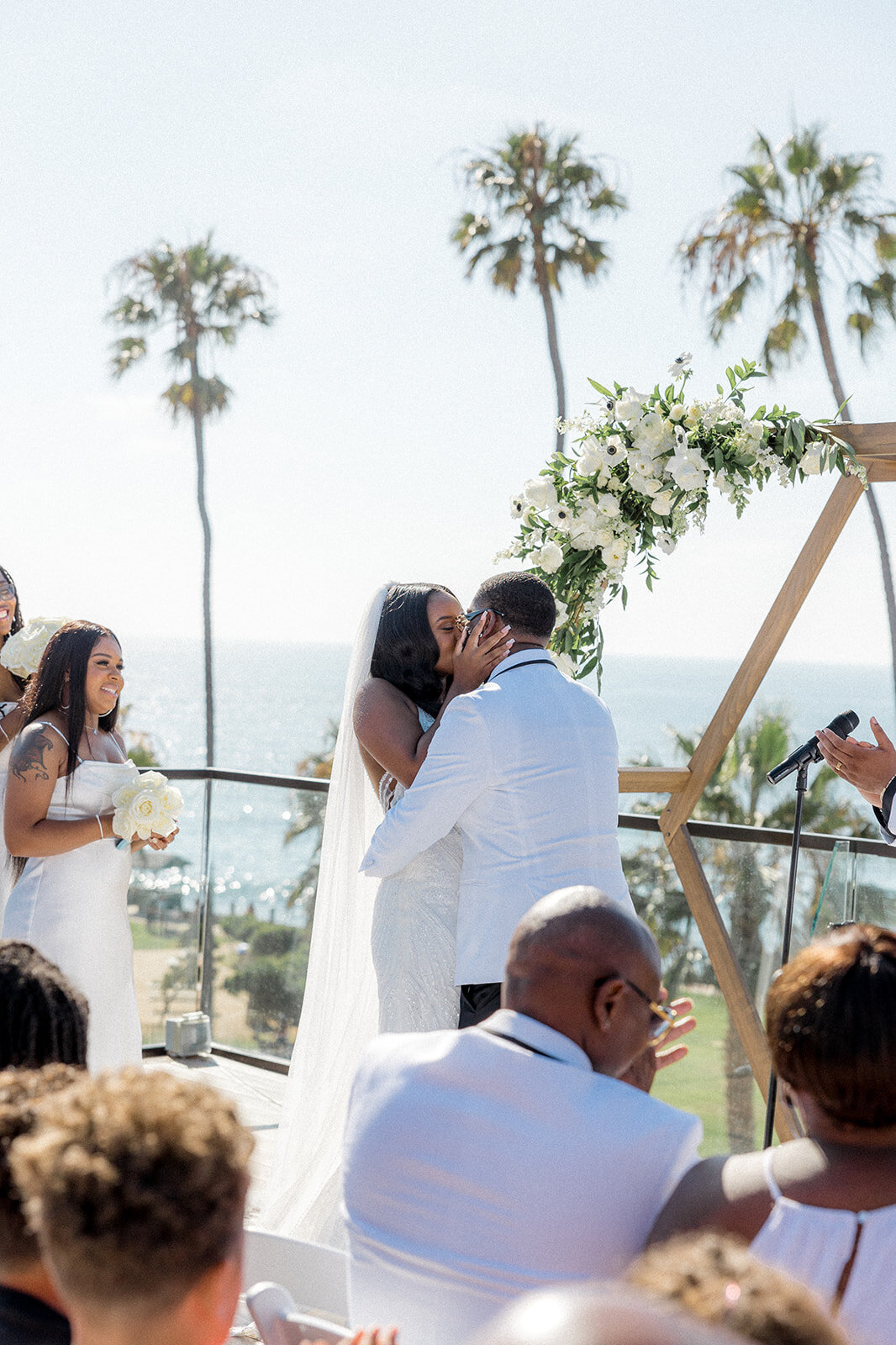 Bride and groom kissing at the alter and wedding party clapping in San Diego