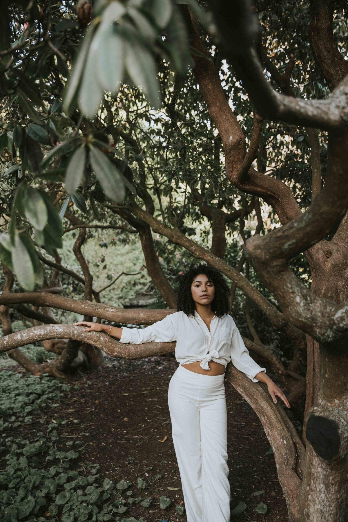 Picture of girl in all white leaning on tree