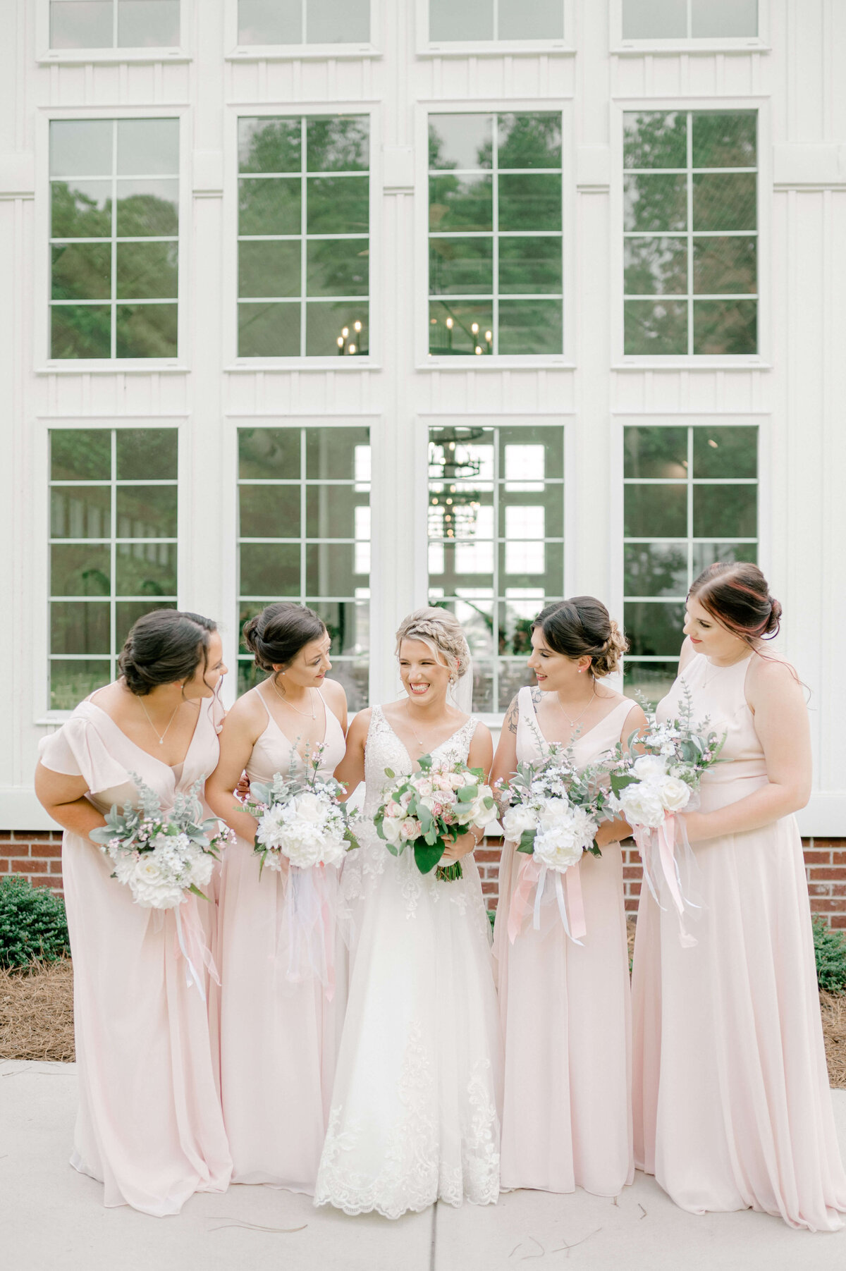 Bridesmaids in pink dresses looking bride suring wedding party photos