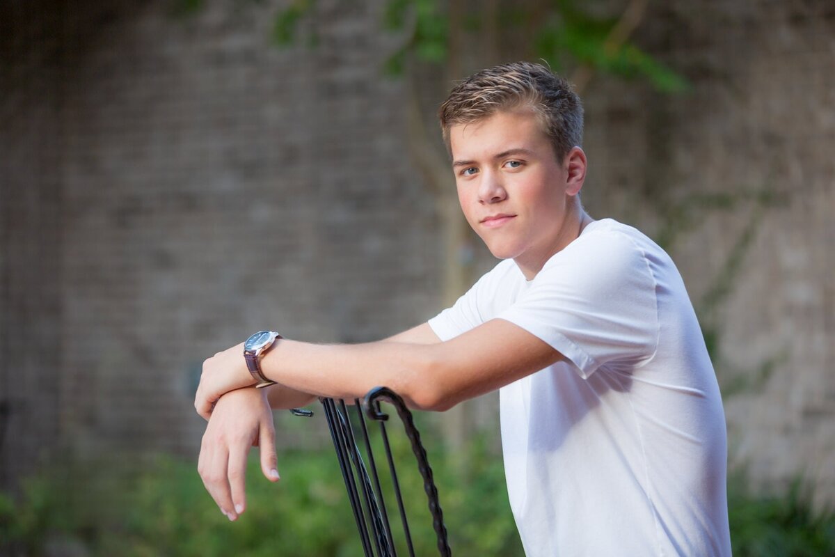 Senior portrait of a boy sitting backwards in a chair in Senoia Georgia.