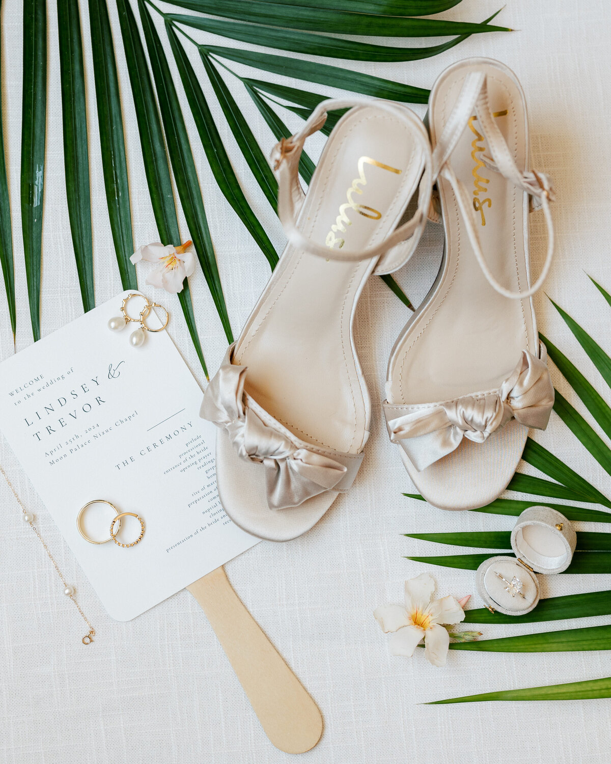 Wedding shoes and gold rings styled with palm leaves, a tropical flat lay from a Cancun wedding by a Philly photographer.