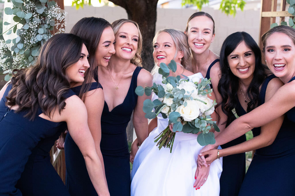 Bride smiling as her bridal party surrounds her.