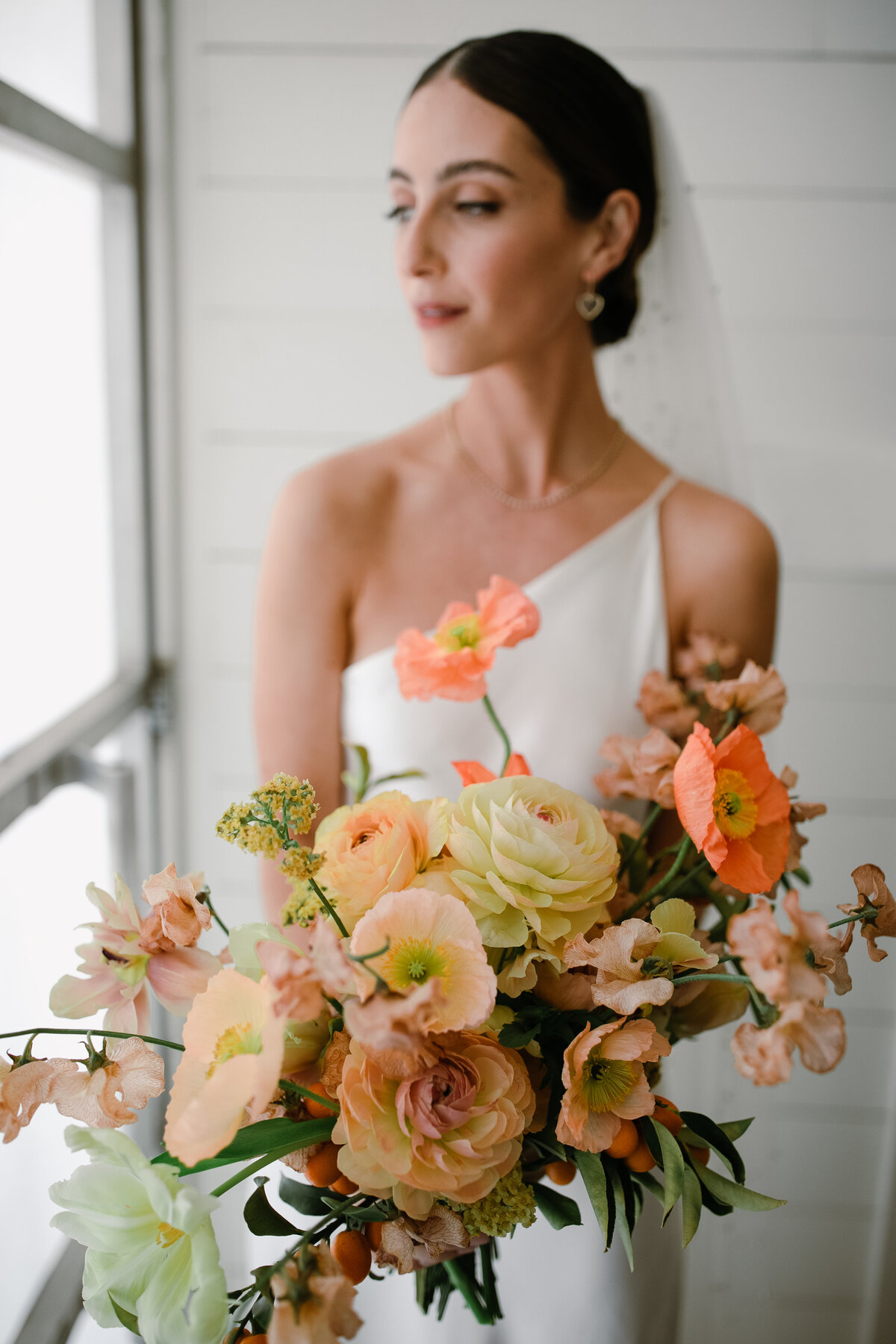 Bride holding large bouquet of orange, peach and ivory florals for Prospect House Wedding, Austin