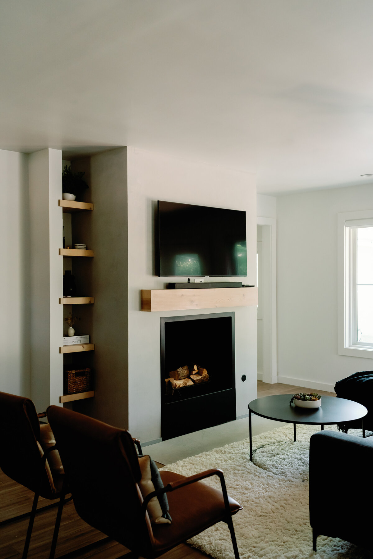 concrete fireplace with wood mantle, leather chairs and circle coffee table