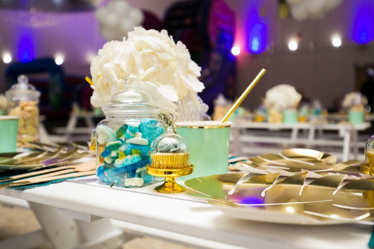 Kids party table with sweet jar, cup cake, cup, plate and floral display