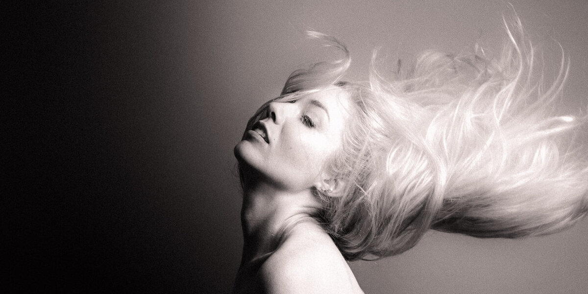 Ethereal studio portrait of a woman in profile with windblown hair, softly lit to create a dreamy, sensual expression.