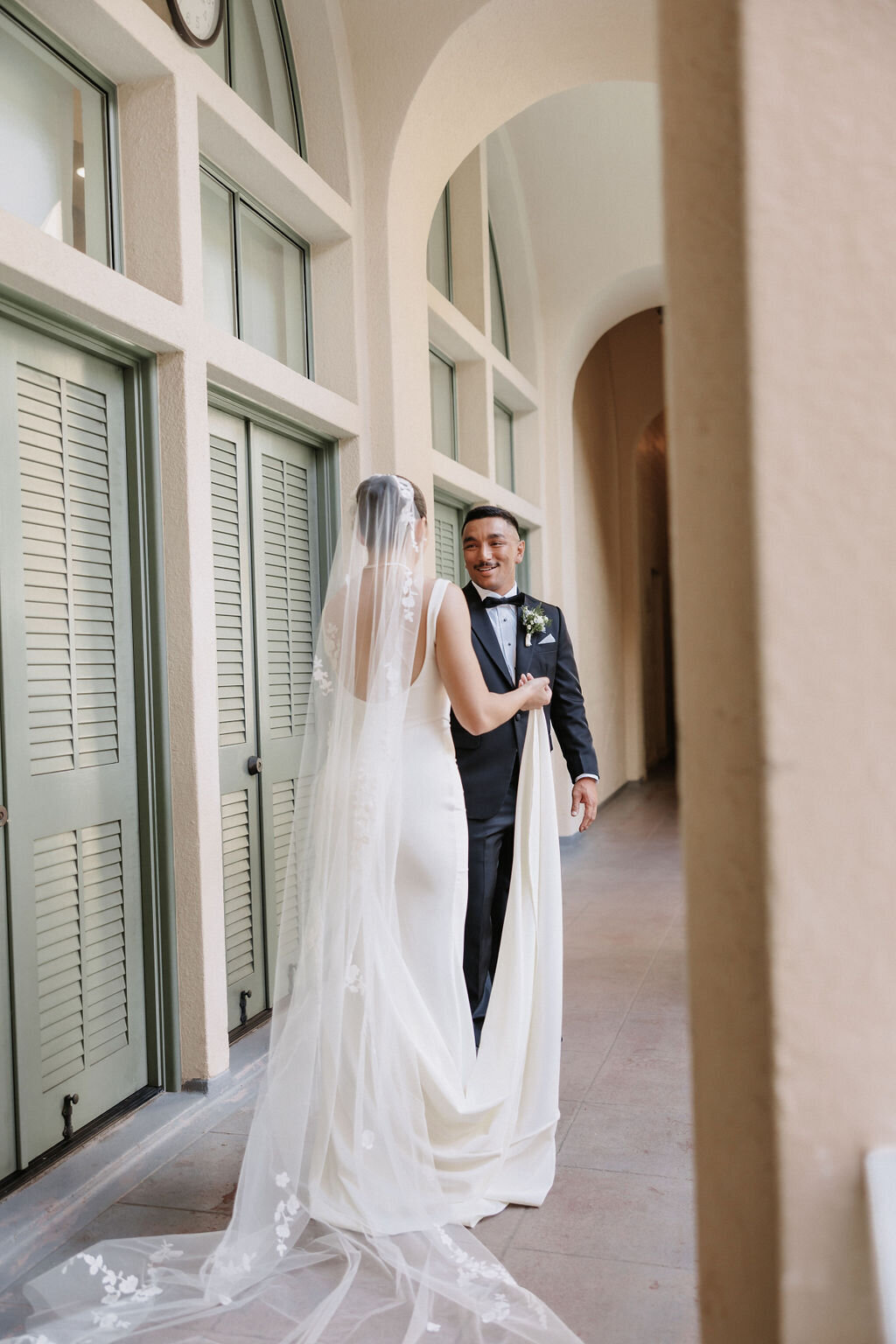bride and groom facing each other under arches by the pool at cafe julia hawaii