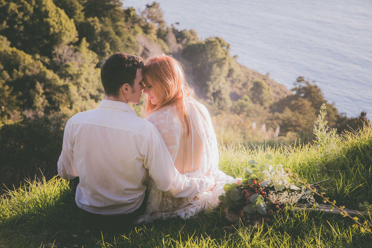 Couple touches foreheads with Big Sur views.