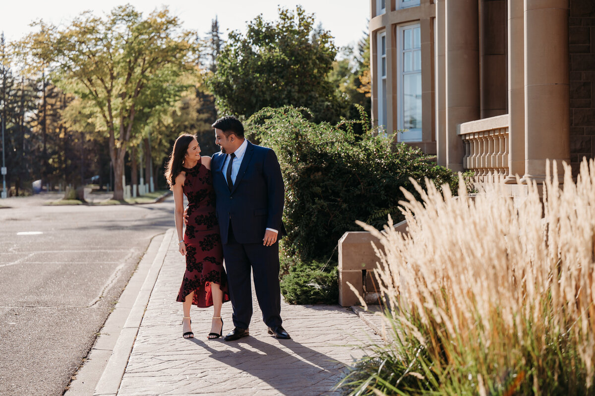 couple bumps hips and laughs on sidewalk in front of historical building