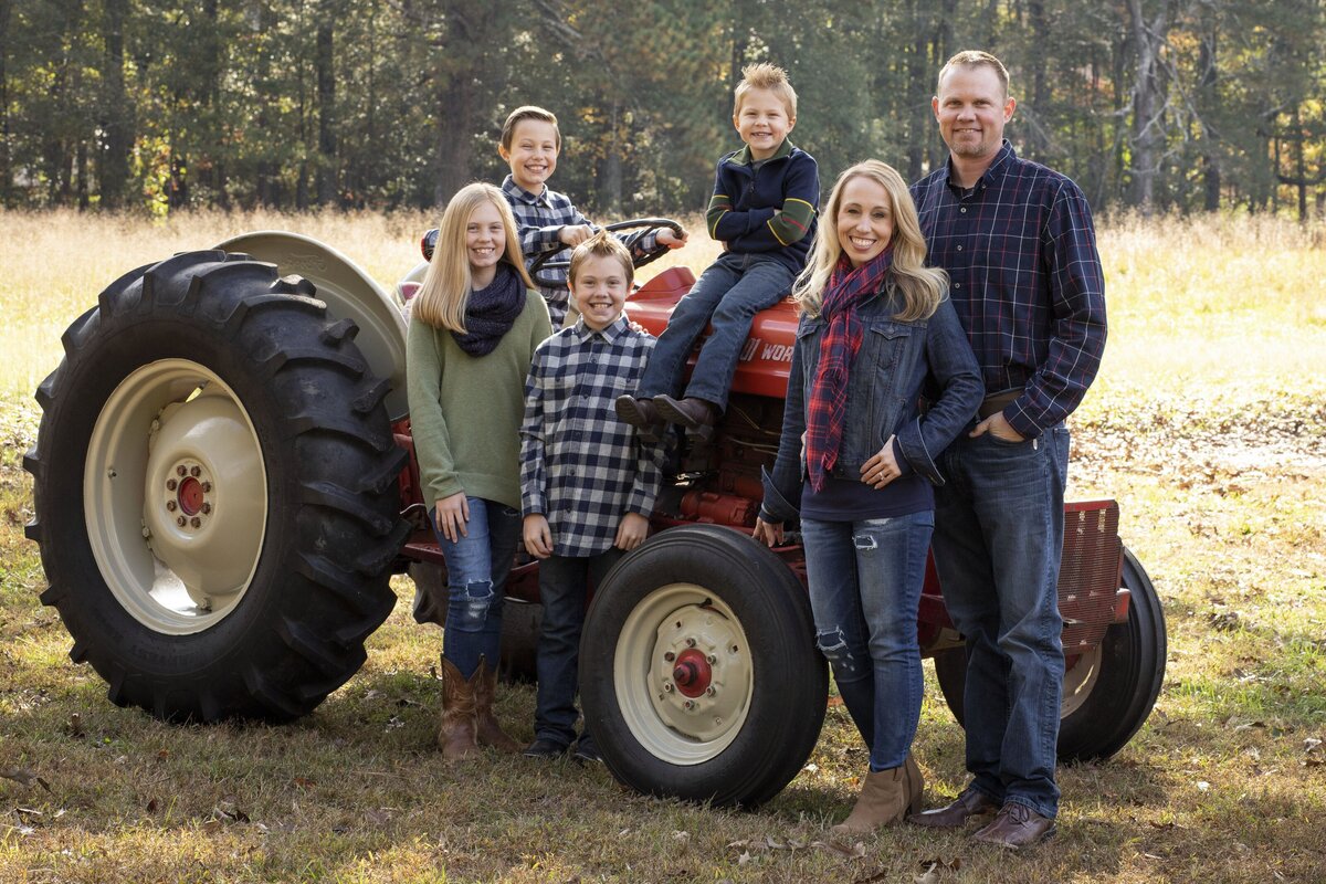 family posing for picture on red tractor