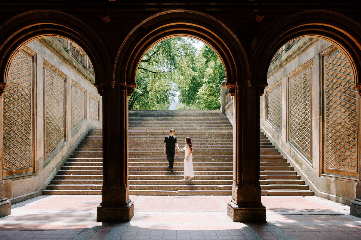 couple walking down outdoor stairs before archways