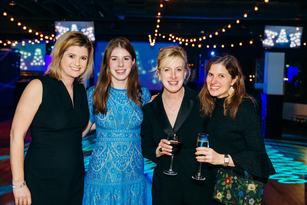 A group of women stand with drinks by the dance floor